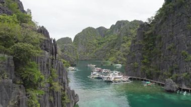 El Nido, Palawan, Filipinler 'deki muhteşem Büyük Göl manzarası. Kayalık bir kıyıya yakın okyanusta yüzen tekneler. 