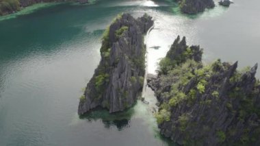 El Nido, Palawan, Filipinler 'deki muhteşem Büyük Göl manzarası. Kayalık bir kıyıya yakın okyanusta yüzen tekneler. 