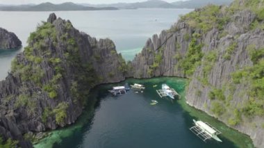El Nido, Palawan, Filipinler 'deki muhteşem Büyük Göl manzarası. Kayalık bir kıyıya yakın okyanusta yüzen tekneler. 
