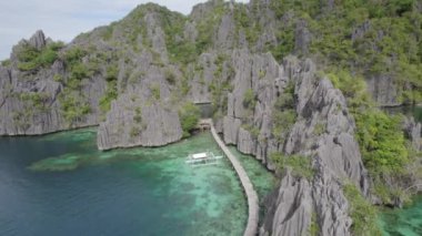 El Nido, Palawan, Filipinler 'deki muhteşem Büyük Göl manzarası. Kayalık bir kıyıya yakın okyanusta yüzen tekneler. 