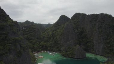 El Nido, Palawan, Filipinler 'deki muhteşem Büyük Göl manzarası. Kayalık bir kıyıya yakın okyanusta yüzen tekneler. 