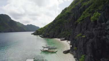 El Nido, Palawan, Filipinler 'deki muhteşem Büyük Göl manzarası. Kayalık bir kıyıya yakın okyanusta yüzen tekneler.   
