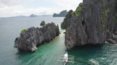 Kayalık kıyı şeridi ve yüzen tekneleri olan güzel mavi okyanuslar. Palawan, Filipinler 'de İnanılmaz Büyük Göl