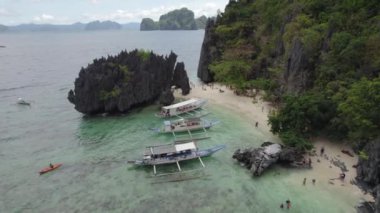 Kayalık kıyı şeridi ve yüzen tekneleri olan güzel mavi okyanuslar. Palawan, Filipinler 'de İnanılmaz Büyük Göl