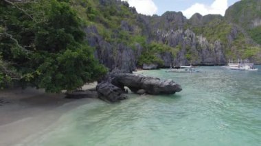 Kayalık kıyı şeridi ve yüzen tekneleri olan güzel mavi okyanuslar. Palawan, Filipinler 'de İnanılmaz Büyük Göl