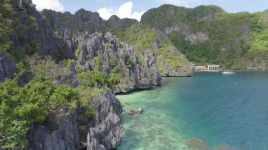 Kayalık kıyı şeridi ve yüzen tekneleri olan güzel mavi okyanuslar. Palawan, Filipinler 'de İnanılmaz Büyük Göl