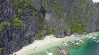 Uzaklarda yüzen tekneleri olan kayalık bir kıyı şeridi olan güzel mavi bir okyanus. Twin Lagoon, Coron, Palawan Filipinlerindeki Karst Kayalıkları.