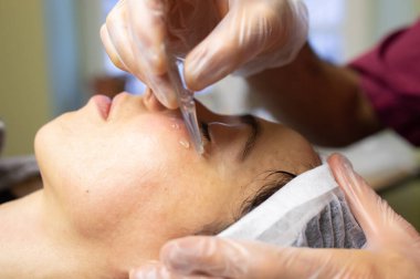 Güzellik salonunda yüz bakımı gören genç bir kadın.                    