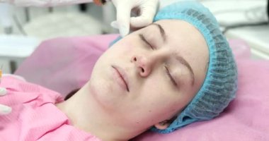 Modern güzellik salonunda gözleri kapalı genç bir kadına gençleştirici iğne yapan profesyonel kadın güzellik uzmanı.. 
