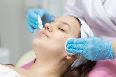 Modern güzellik salonundaki genç bayana gençleştirici prosedür uygulayan profesyonel kadın güzellik uzmanı..              