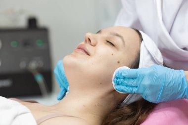 Modern güzellik salonundaki genç bayana gençleştirici prosedür uygulayan profesyonel kadın güzellik uzmanı..              