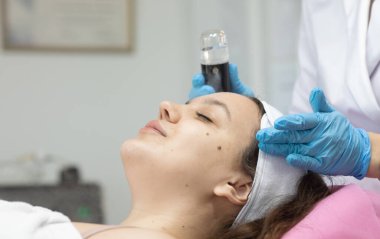 Modern güzellik salonundaki genç bayana gençleştirici prosedür uygulayan profesyonel kadın güzellik uzmanı..              