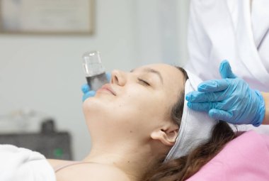 Modern güzellik salonundaki genç bayana gençleştirici prosedür uygulayan profesyonel kadın güzellik uzmanı..              