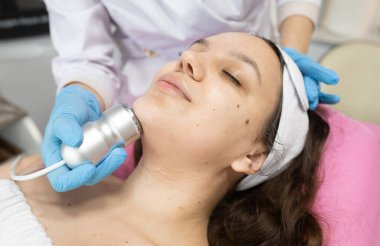 Klinikteki bir kozmetikçide yüz yenileme ameliyatı için gerekli radyoaktivite prosedürü. Estetik tıp kavramı. Yüzün ultrasonik temizliği     