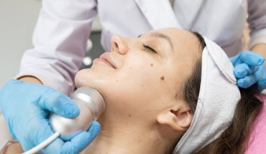 Klinikteki bir kozmetikçide yüz yenileme ameliyatı için gerekli radyoaktivite prosedürü. Estetik tıp kavramı. Yüzün ultrasonik temizliği     