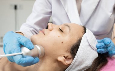 Klinikteki bir kozmetikçide yüz yenileme ameliyatı için gerekli radyoaktivite prosedürü. Estetik tıp kavramı. Yüzün ultrasonik temizliği     