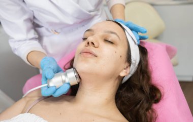 Klinikteki bir kozmetikçide yüz yenileme ameliyatı için gerekli radyoaktivite prosedürü. Estetik tıp kavramı. Yüzün ultrasonik temizliği     