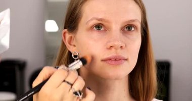 Profesyonel makyöz güzel genç bir kadınla çalışıyor. Makyaj sanatçısı cazibe modeline makyaj yapıyor             