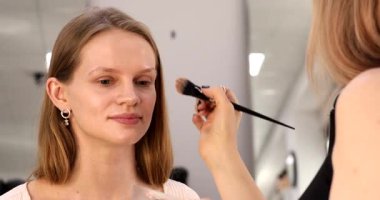 Profesyonel makyöz güzel genç bir kadınla çalışıyor. Makyaj sanatçısı cazibe modeline makyaj yapıyor             