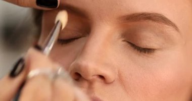 Stüdyoda makyajlı genç ve güzel bir kız. Makyöz güzellik salonuna göz farı sürüyor, yakın plan.                