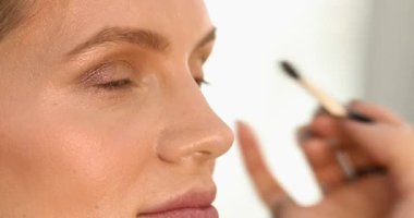 Stüdyoda makyajlı genç ve güzel bir kız. Makyöz güzellik salonuna göz farı sürüyor, yakın plan.                