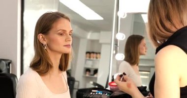 Makyöz güzellik stüdyosunda çalışıyor. Profesyonel makyaj ustası tarafından başvurulan kadın portresi.             