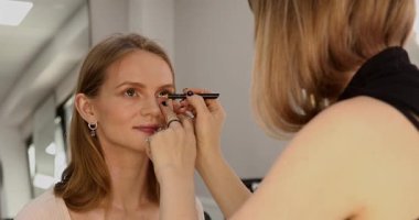 Makyaj sanatçısı güzellik salonunda çalışıyor. Profesyonel makyaj ustası tarafından uygulanan kadın portresi.       