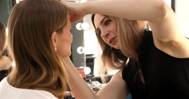 Makyöz güzellik stüdyosunda çalışıyor. Profesyonel makyaj ustası tarafından başvurulan kadın portresi.             