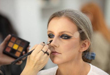Güzellik salonunda genç bir bayanın makyajını yapan profesyonel makyözün yakın çekimi. Profesyonel göz makyajı modeli. 