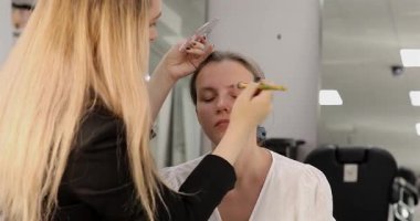 Profesyonel makyöz güzellik salonundaki güzel kadın modeline makyaj yapıyor..           