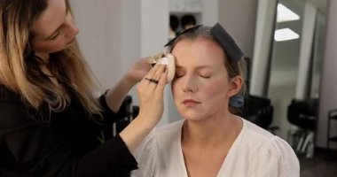 Profesyonel makyöz güzellik salonundaki güzel kadın modeline makyaj yapıyor..           