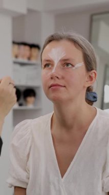 Makyöz, güzellik salonunda genç bir kadının profesyonel makyajını yapıyor.                              