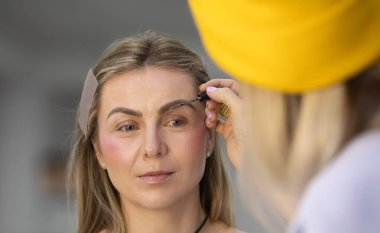 Profesyonel makyöz güzellik salonundaki güzel bayan modellere makyaj yapıyor..               