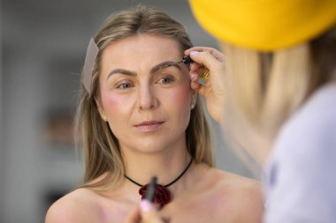 Profesyonel makyöz güzellik salonundaki güzel bayan modellere makyaj yapıyor..               