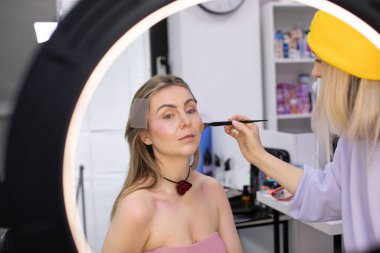 Profesyonel makyöz güzellik salonundaki güzel bayan modellere makyaj yapıyor..               