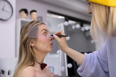 Profesyonel makyöz güzellik salonundaki güzel bayan modellere makyaj yapıyor..               