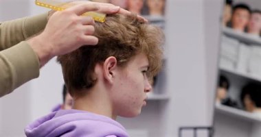 Berber dükkanında saçını kestiren bir adam. Erkek kuaför çalışıyor..              