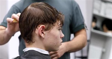 Berber dükkanında saçını kestiren bir adam. Erkek kuaför çalışıyor..              