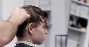 Berber dükkanında saçını kestiren bir adam. Erkek kuaför çalışıyor..              