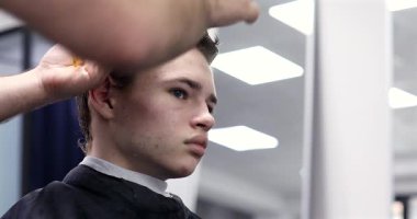 Berber dükkanında saçını kestiren bir adam. Erkek kuaför çalışıyor..              