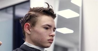 Berber dükkanında saçını kestiren bir adam. Erkek kuaför çalışıyor..              