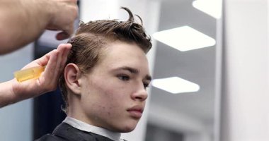 Berber dükkanında saçını kestiren bir adam. Erkek kuaför çalışıyor..              