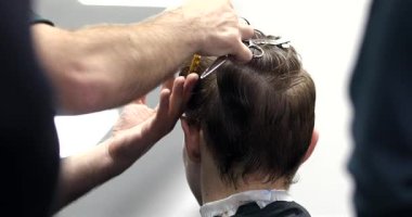 Berber dükkanında saçını kestiren bir adam. Erkek kuaför çalışıyor..              