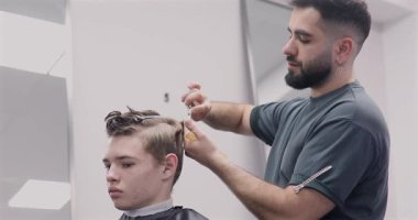 Berber dükkanında saçını kestiren bir adam. Erkek kuaför çalışıyor..              