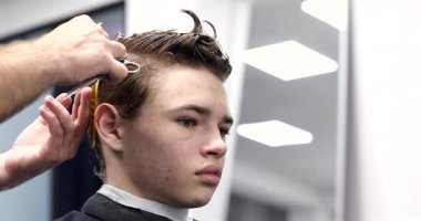 Berber dükkanında saçını kestiren bir adam. Erkek kuaför çalışıyor..              