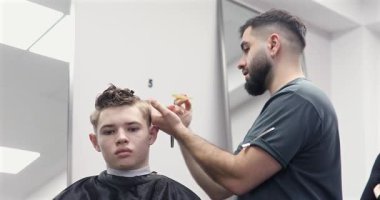 Berber dükkanında saçını kestiren bir adam. Erkek kuaför çalışıyor..              