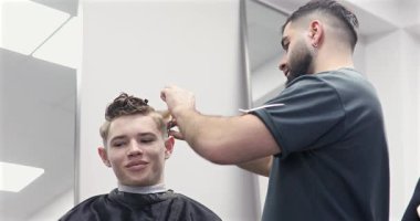 Berber dükkanında saçını kestiren bir adam. Erkek kuaför çalışıyor..              