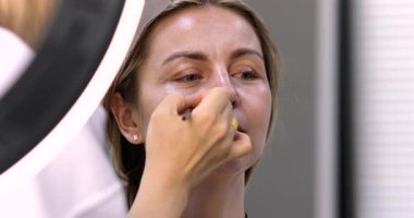 Profesyonel makyöz güzellik salonundaki güzel kadın modeline makyaj yapıyor..           