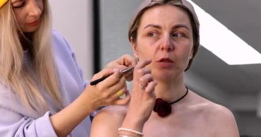 Profesyonel makyöz güzellik salonundaki güzel kadın modeline makyaj yapıyor..           