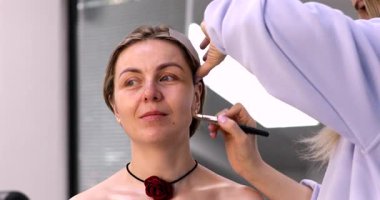 Profesyonel makyöz güzellik salonundaki güzel kadın modeline makyaj yapıyor..           